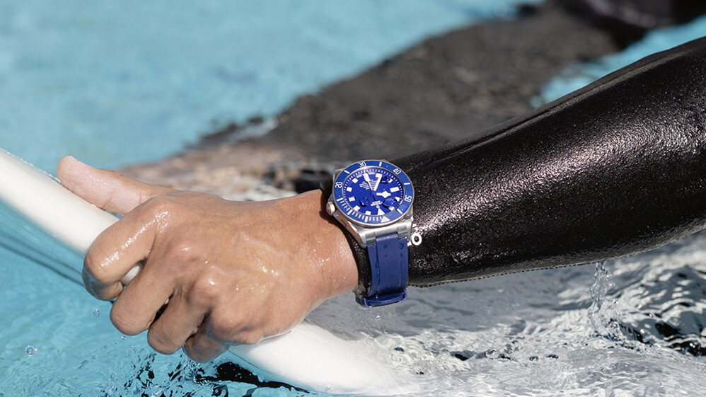 Hand on surfboard with a TUDOR watch